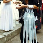 Group of transparent umbrellas held by a woman at an outdoor event.