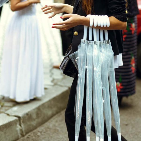 Group of transparent umbrellas held by a woman at an outdoor event.