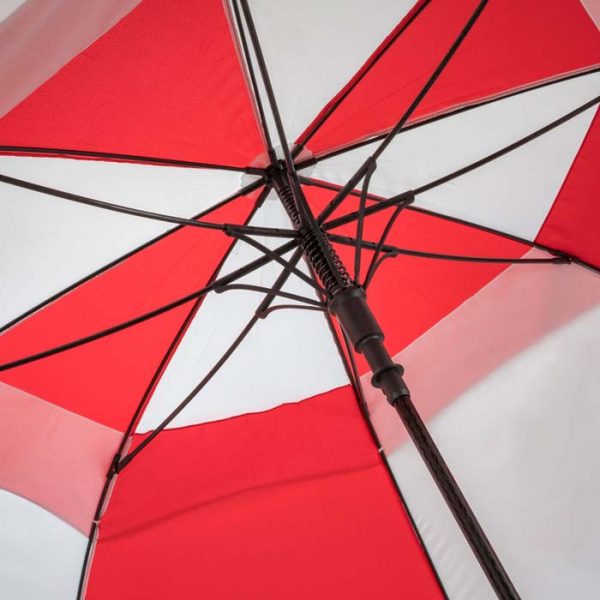 Close-up of a red and white golf umbrella with wind-resistant features.