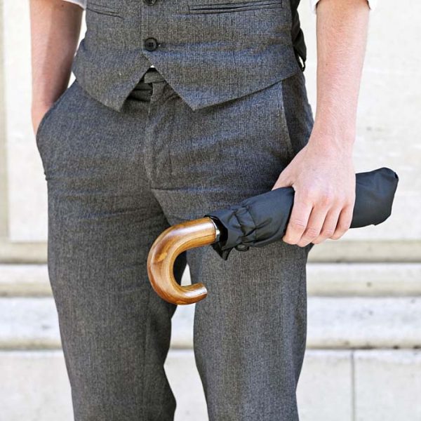 Man holding a compact black umbrella with a wooden handle.