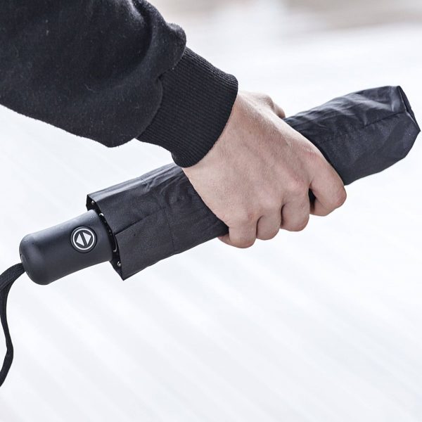 Person holding a compact, automatic open and close umbrella in hand.