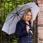Woman with polka dot umbrella in outdoor setting.