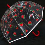 Clear children's umbrella with red strawberry print and red handle.